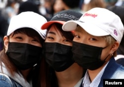 Japanese women wearing masks to prevent pollen allergy and for fashion, pose for photographs at Harajuku shopping district in Tokyo, Japan March 15, 2018. (REUTERS/Kim Kyung-Hoon)