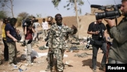 Malian soldier gestures at journalists to leave area of a French air strike in Konna, 430 miles north of Bamako, Jan. 26, 2013.