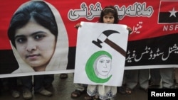 A girl holds a placard next to an image of schoolgirl Malala Yousufzai, who was shot on October 9 by the Taliban, during a rally organized by National Students Federation (NSF) in Lahore October 15, 2012. 