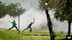 Protesters caught in teargas, hurl stones at police, unseen, during violent clashes in Sasolburg, South Africa, January 22 2013.