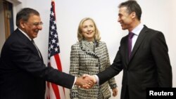 El secretario de defensa, Leon Panetta, y el secretario general de la OTAN, Anders Rasmussen, se saludan, mientras observa la secretaria de Estado, Hillary Clinton.