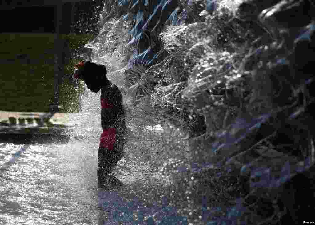 پارک میں ایک بچہ گرمی سے بچنے کے لیے فوارے کے پانی سے لطف اندوز ہو رہا ہے۔ &nbsp; &nbsp; 