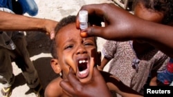 A health worker drops anti-polio vaccine into the mouth of a Somali child in the capital Mogadishu September 10, 2006. Health workers today began a polio immunisation drive in Kenya, Somalia and Ethiopia. REUTERS/Shabelle Media (SOMALIA) - RTR1H6YV