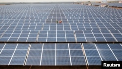 FILE - Workers install photovoltaic solar panels at the Gujarat solar park under construction in Charanka village in Patan district of the western Indian state of Gujarat, India.