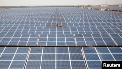 FILE - Workers install photovoltaic solar panels at the Gujarat solar park under construction in Charanka village in Patan district of the western Indian state of Gujarat, India. India is planning new large-scale installations of the technology on hydropower reservoirs and other water bodies in Tamil Nadu, Jharkhand and Uttarakhand states, and in the Lakshadweep islands