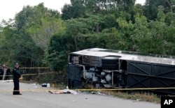 The lifeless body of a passenger lies next to an overturned bus in Mahahual, Quintana Roo state, Mexico, Tuesday, Dec. 19, 2017.