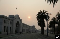 FILE - Smoke and haze from wildfires obscures the Embarcadero, Nov. 15, 2018, in San Francisco.