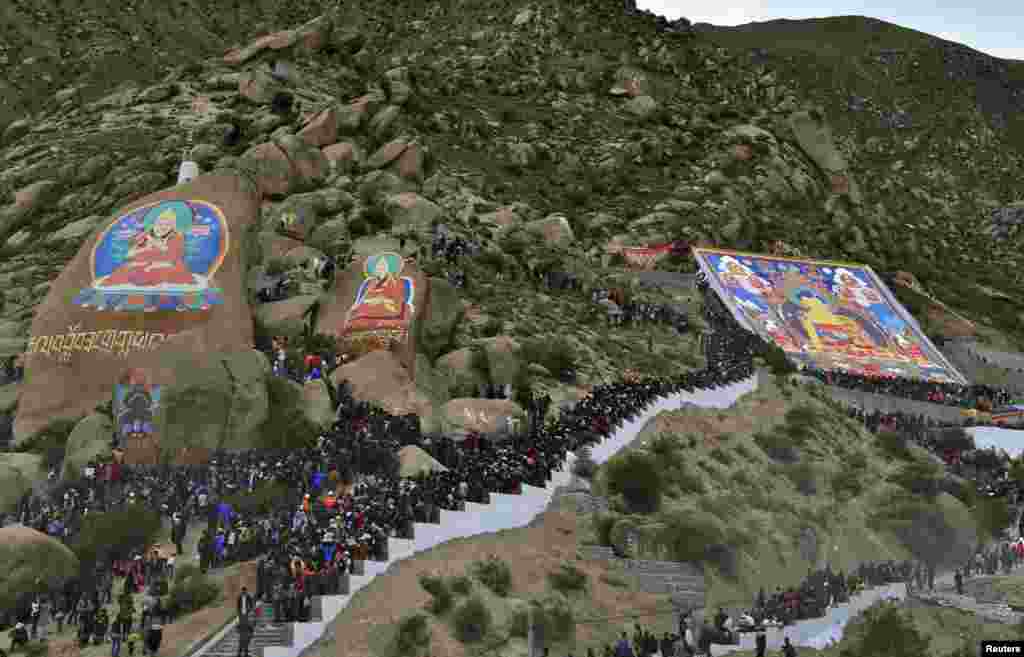 Tibetan Buddhists and tourists view a giant thangka, a religious silk embroidery or painting displaying the Buddha portrait, during the Shoton Festival at Drepung Monastery in Lhasa, Tibet Autonomous Region.