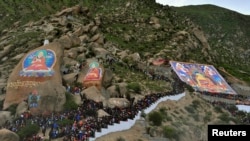 Tibetan Buddhists and tourists view a giant thangka, a religious silk embroidery or painting displaying the Buddha portrait, during the Shoton Festival at Drepung Monastery in Lhasa, Tibet Autonomous Region August 6, 2013. 