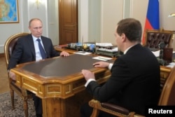 Russian President Vladimir Putin talks with PM Dmitry Medvedev during their meeting outside Moscow, Apr. 19, 2014.