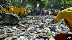 A Manila City Hall employee throws pirated DVDs (Digital Video Discs) onto the path of the steamrollers as they are destroyed, file photo. 