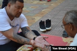 Sang Nin, 40, who was deported from the U.S. on Dec. 19, 2018, asks a fortune teller about his future while on a tour at Wat Ampe Phnom in Cambodia.