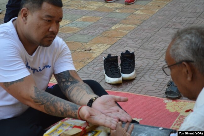 Sang Nin, 40, who was deported from the U.S. on Dec. 19, 2018, asks a fortune teller about his future while on a tour at Wat Ampe Phnom in Cambodia.
