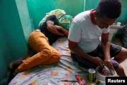 A Venezuelan migrant prepares food as another rests at a temporary shelter in Tumbes, Peru, Aug. 25, 2018.