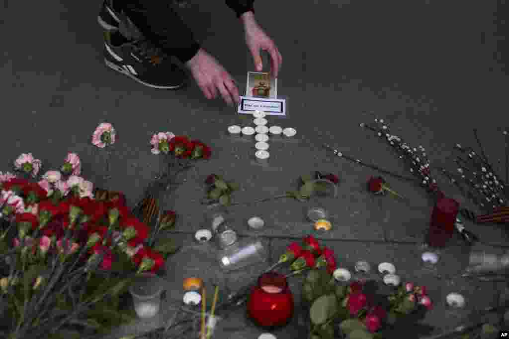 A man lights candles at a symbolic memorial outside Sennaya subway station in St. Petersburg, Russia. A bomb blast tore through a subway train, killing several people and wounding many more.