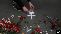 A man lights candles arranged in a form of a cross at a symbolic memorial outside Sennaya subway station in St. Petersburg, Russia, April 4, 2017. 