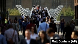 During a 24 hour London underground train strike, people walk across the Millennium Bridge for pedestrians in London, Thursday, July 9, 2015. 