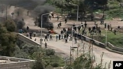 In this image made from television, protesters are seen near a barricade in Daraa, Syria, April 8, 2011