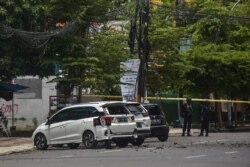 Polisi berjaga di samping kendaraan yang rusak setelah ledakan di luar sebuah gereja di Makassar pada 28 Maret 2021. (Foto: AFP/Indra Abriyanto)