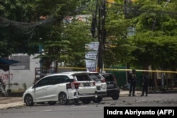 Polisi berjaga di samping kendaraan yang rusak setelah ledakan di luar sebuah gereja di Makassar pada 28 Maret 2021. (Foto: AFP/Indra Abriyanto)