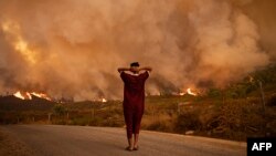 Une femme regarde des incendies de forêt ravager une forêt dans la région de Chefchaouen, dans le nord du Maroc, le 15 août 2021.