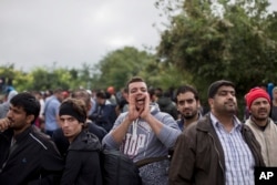 FILE - A man shouts while people wait to clear a police line as they entered into Croatia from Serbia, in Babska, Croatia, Sept. 25, 2015.