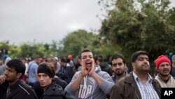 A man shouts while people wait to clear a police line as they entered into Croatia from Serbia, in Babska, Croatia, Sept. 25, 2015.