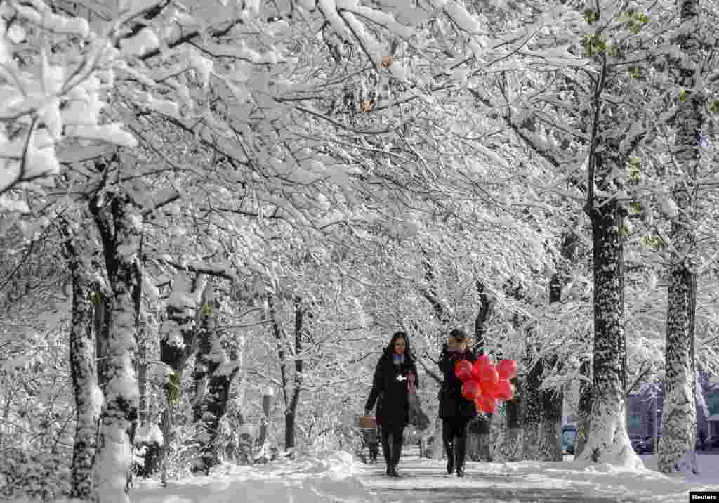 Women walk along a snow-covered alley in Almaty, Kazakhstan.