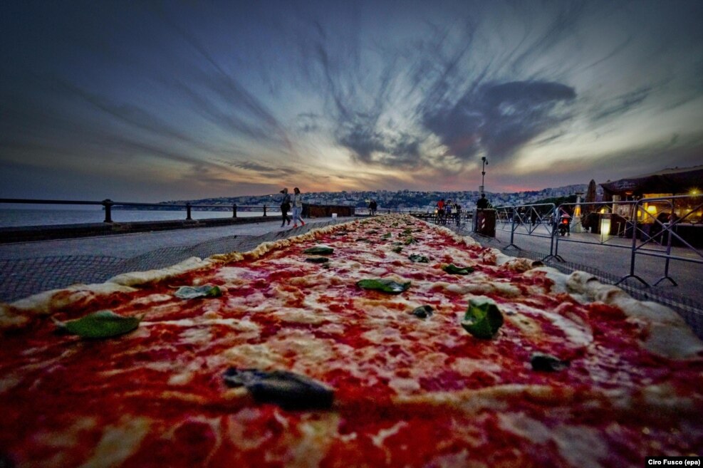 A two-kilometer long Neapolitan pizza made to break a Guinness World Record for the longest pizza ever made, is seen stretching along the city waterfront, in Naples, Italy, May 18, 2016.