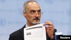 Syrian U.N. Ambassador Bashar Ja'afari shows a document to reporters at the United Nations Headquarters in New York, Sept. 12, 2013.