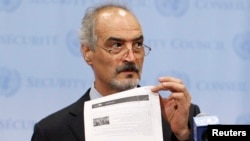 Syrian U.N. Ambassador Bashar Ja'afari shows a document to reporters at the United Nations Headquarters in New York, Sept. 12, 2013.