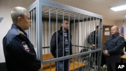 Police officers guards a cage with Greenpeace activist Ruslan Yakushev in a court room, Sept. 26, 2013. 