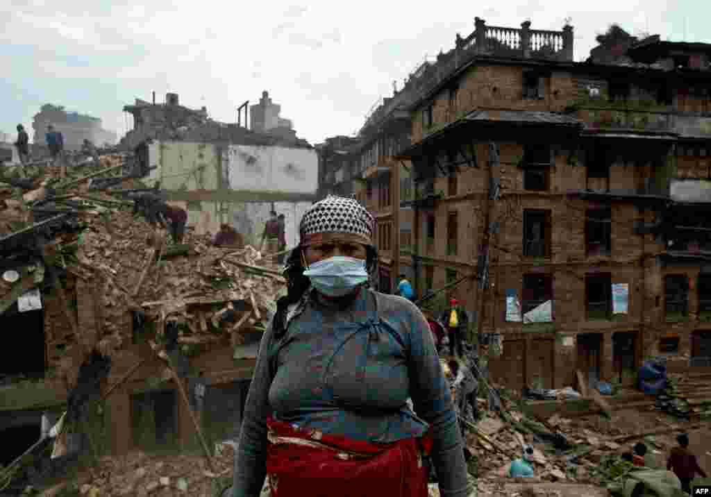 Nepalese woman searches for belongings amidst rubble at the heritage town of Bhaktapur.