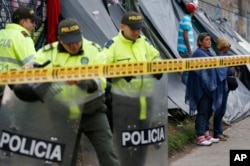 Police stand guard at a makeshift migrant settlement near the main bus terminal in Bogota, Colombia, Nov. 13, 2018.