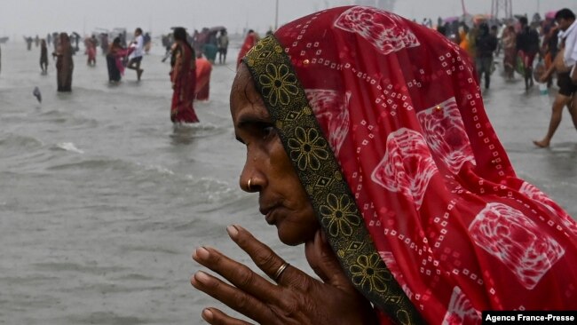 A Hindu pilgrim in India prays as she takes a holy dip at the confluence of Ganges and the Bay of Bengal during the Gangasagar Mela on the occasion of Makar Sankranti, Jan. 14, 2022.