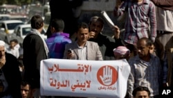 A protester holds a banner with Arabic writing that reads, "The coup does not build a country," protesting against Houthi Shiite rebels who hold the capital, Sanaa, amid a power vacuum as they hold a demonstration in Saturday, Jan. 24, 2015.