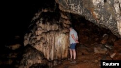 A guide looks at red ocher markings which were painted on stalagmites by Neanderthals about 65,000 years ago, according to an international study, in a prehistoric cave in Ardales, southern Spain, August 7, 2021. (REUTERS/Jon Nazca)