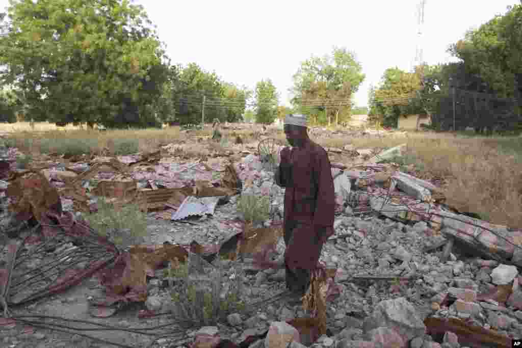 In this Nov. 12, 2010 photo, an unidentified man stand on the remains of the destroyed Boko Haram mosque in Maiduguri, Nigeria. In northeastern Nigeria, far from the battlegrounds of Afghanistan, a group known as the Nigerian Taliban is waging war against