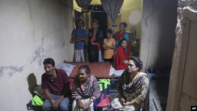 In this May 14, 2019, photo Pakistani Christian Natasha Masih, right front, sits with her family members during an interview in Faisalabad, Pakistan. Natasha begged her mother to bring her home from China, but it took an elaborate scheme devised by a smal