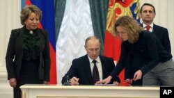 FILE - Russian President Vladimir Putin signs bills formalizing Russia's annexation of Ukraine's Crimean peninsula, in the Kremlin in Moscow, March 21, 2014.