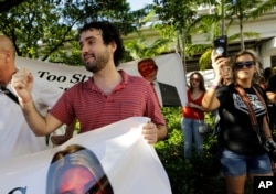 FILE - Thomas Kennedy, 25, protests outside of a rally for Republican presidential nominee Donald Trump, in Miami, Sept. 16, 2016. "One of the things that scares me the most is that this wretched man, Trump, wins," said Kennedy. After becoming a naturalized this year, the 25-year-old immediately registered to vote.