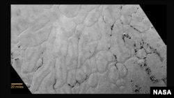 This July 14, 2015, photo provided by NASA shows an image taken from NASA's New Horizons spacecraft showing a new close-up image from the heart-shaped feature on the surface of Pluto that reveals a vast, craterless plain.