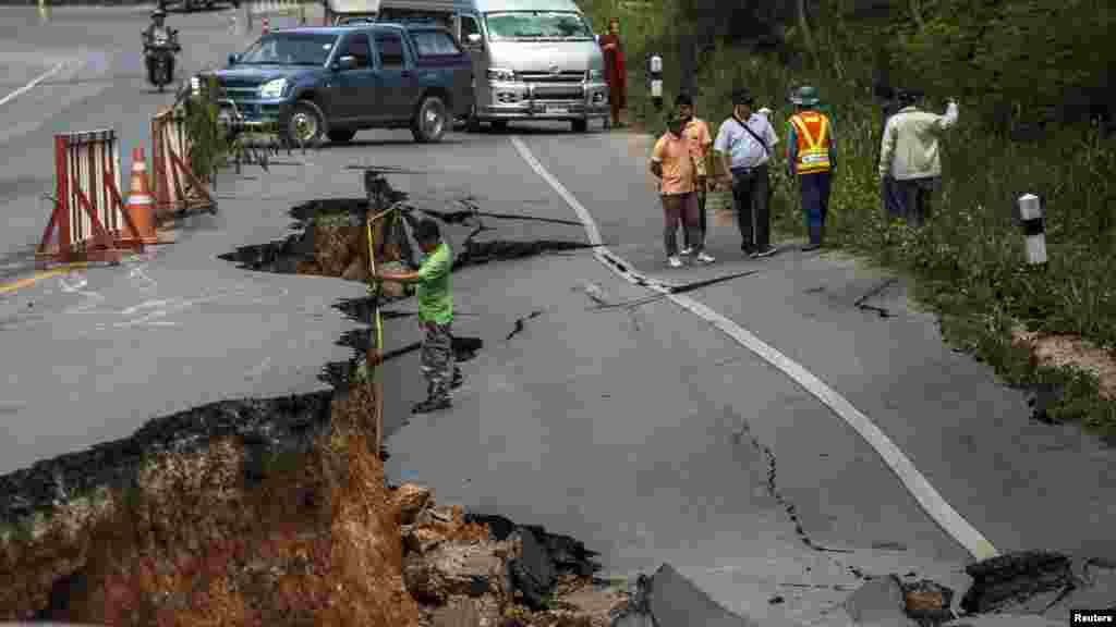 Seorang petugas mengukur kedalaman kerusakan jalan raya akibat gempa bumi 5 Mei 2014, di Chiang Rai, Thailand utara, 6 Mei 2014.