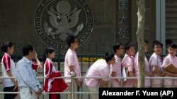 Chinese students wait outside the U.S. Embassy for their visa application interviews in Beijing, China.