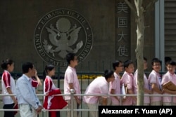 Chinese students wait outside the U.S. Embassy for their visa application interviews in Beijing, China.