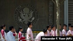 FILE - Chinese students wait outside the U.S. Embassy for their visa application interviews in Beijing, China. The Trump administration may expel thousands of Chinese graduate students enrolled at universities in the U.S. 