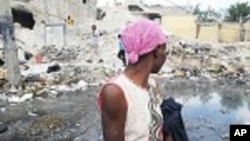 A Haitian woman waiting for a taxi in Port-au-Prince looks at earthquake damage on January 9, 2012. According to the UN some 50 percent of the rubble left by the January 12, 2010 earthquake still litters the Haitian capital.