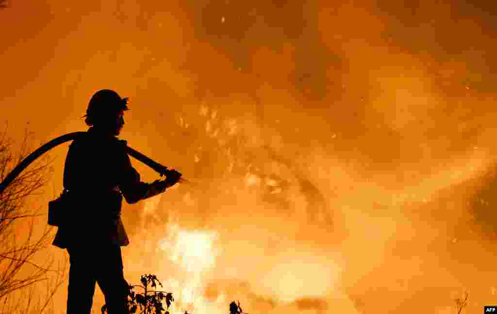 A firefighter battles a wildfire as it burns along a hillside near homes in Santa Paula, California.