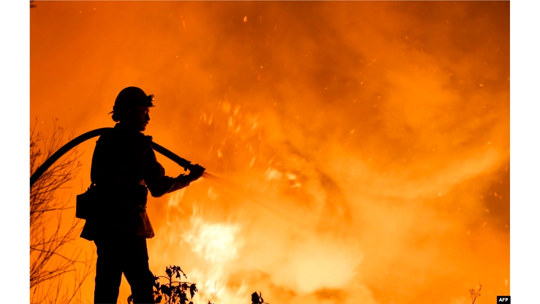 A firefighter battles a wildfire as it burns along a hillside near homes in Santa Paula, California, on December 5, 2017.