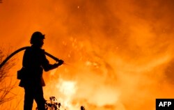 A firefighter battles a wildfire as it burns along a hillside near homes in Santa Paula, California, on December 5, 2017.